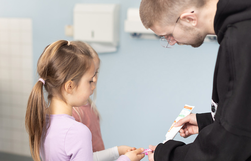 Sozialassistenzschüler hilft Kind beim Zähneputzen.