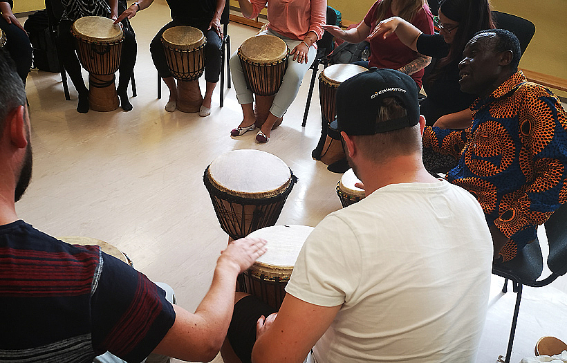Sozialassistenten musizieren gemeinsam in einem Stuhlkreis mit einem Workshopleiter und üben ihr Rhythmusgefühl beim Trommeln. Foto: DPFA Zwickau
