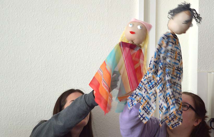 DPFA Zwickau Sozialassistentenausbildung Projekt Puppentheater: Zwei Schülerinnen spielen mit den handpuppen in der Hand für ihre Mitschüler:innen.
